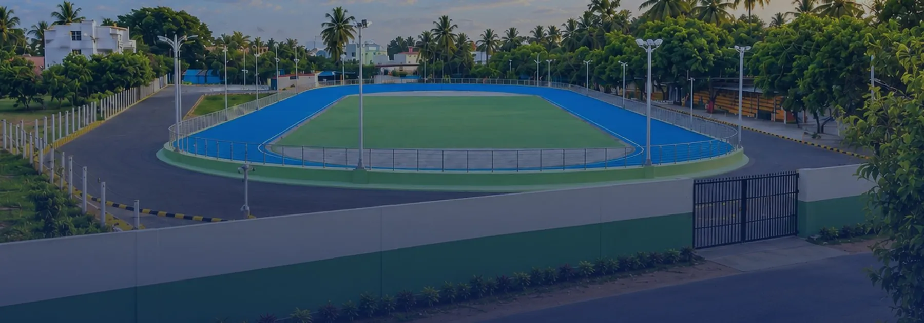 The blue skating track and green infield of the Pollachi rink, ringed by floodlights and coconut palms